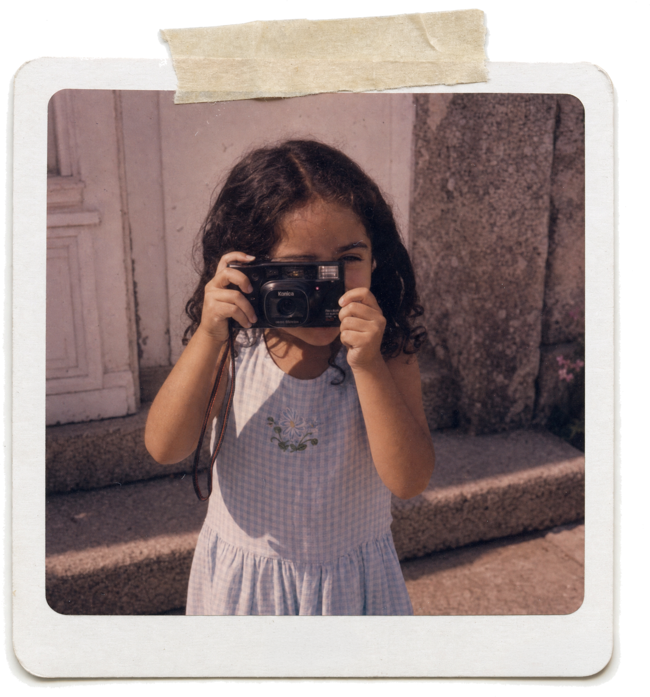 Arantxa as a child in Galicia, holding a compact film camera up to her eye