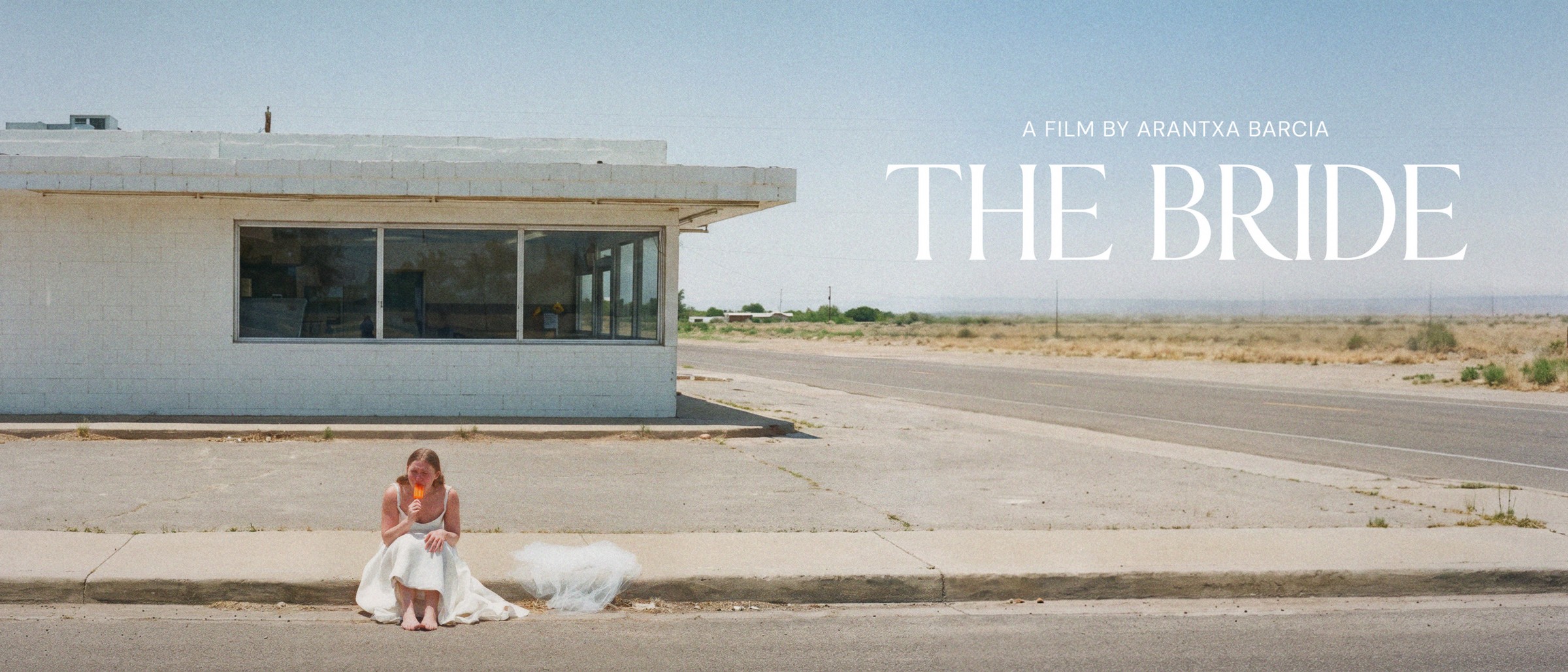 The Bride, a bride sitting on a desert curb eating a popsicle while a school bus pulls up