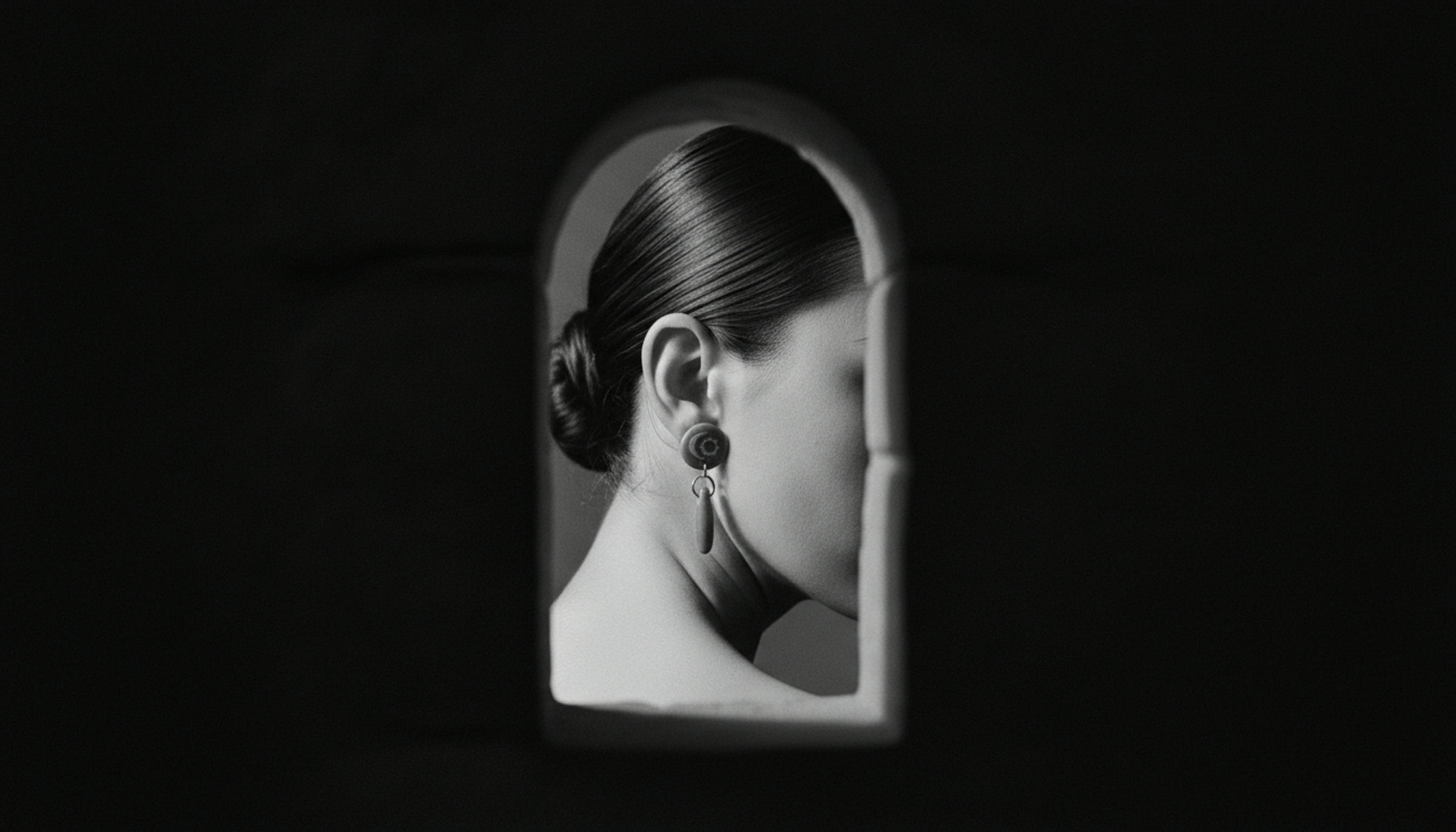 A woman in profile wearing the earring, framed inside a lit archway