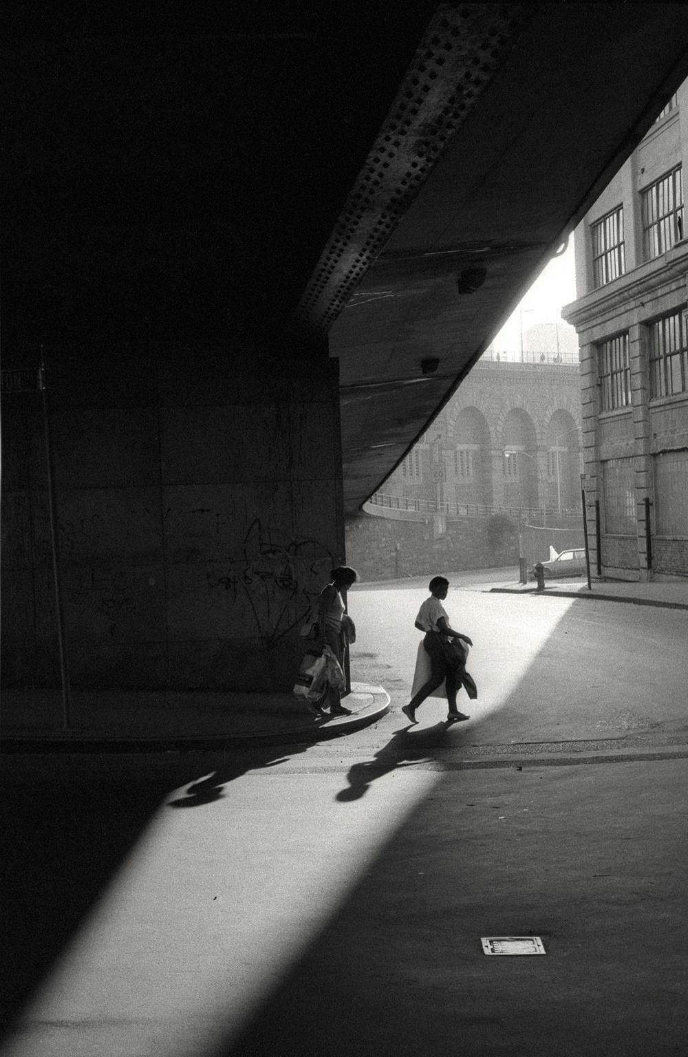 A child crossing a dark arcade into the light