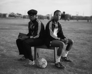 Two young men sitting on a bench with a football