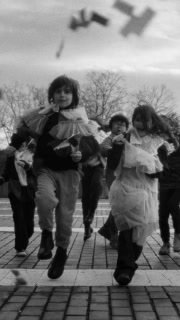 Children running through a square as pigeons scatter