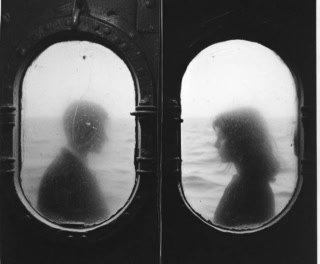 Two figures seen through a pair of ship portholes