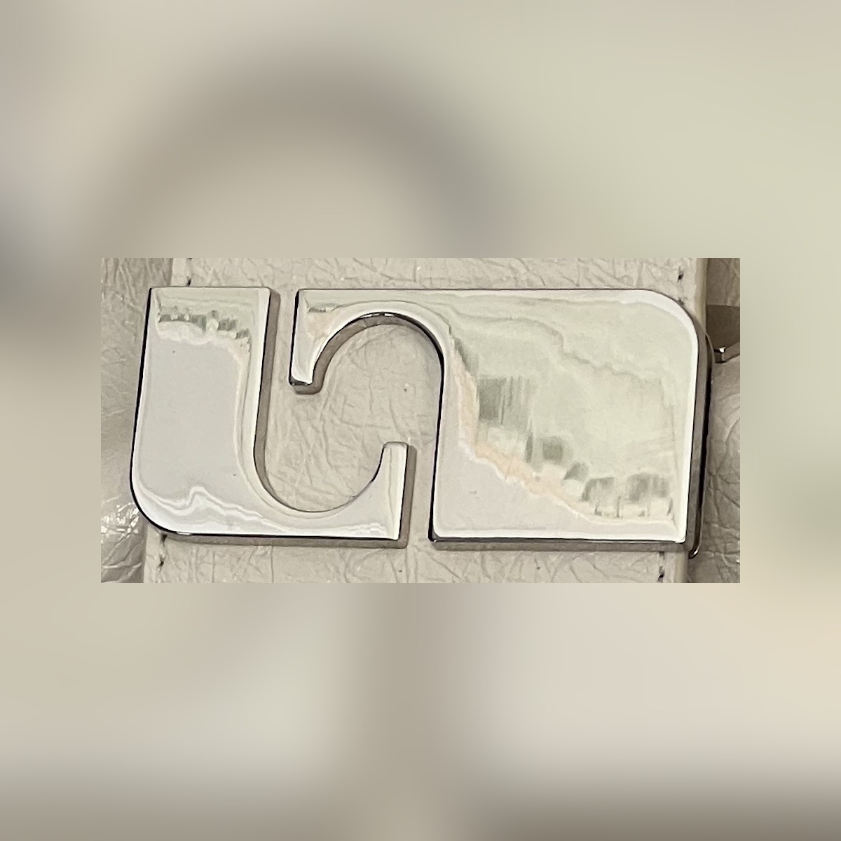 Macro photograph of the silver Laagam clasp on cream leather