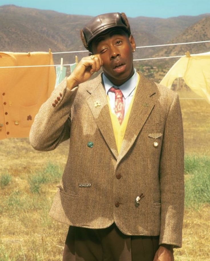 A portrait in tweed and a leather cap against a hillside