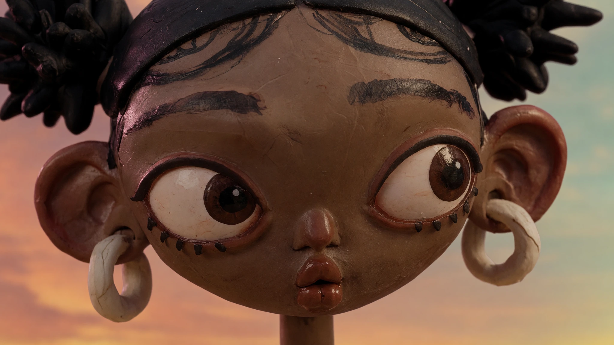 Extreme close-up of Aaliyah against a dusk sky, fingerprints and tool marks visible in the clay